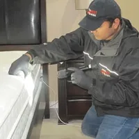 Bed bug inspection technician checking a mattress and bed frame for signs of infestation in San Diego, CA